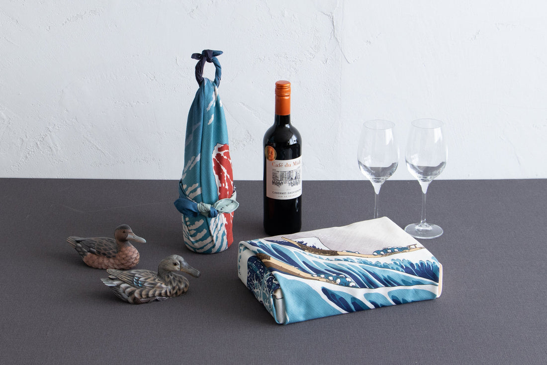 Furoshiki wrapped around a wine bottle tied, and another Furoshiki wrapped around a rectangular gift box