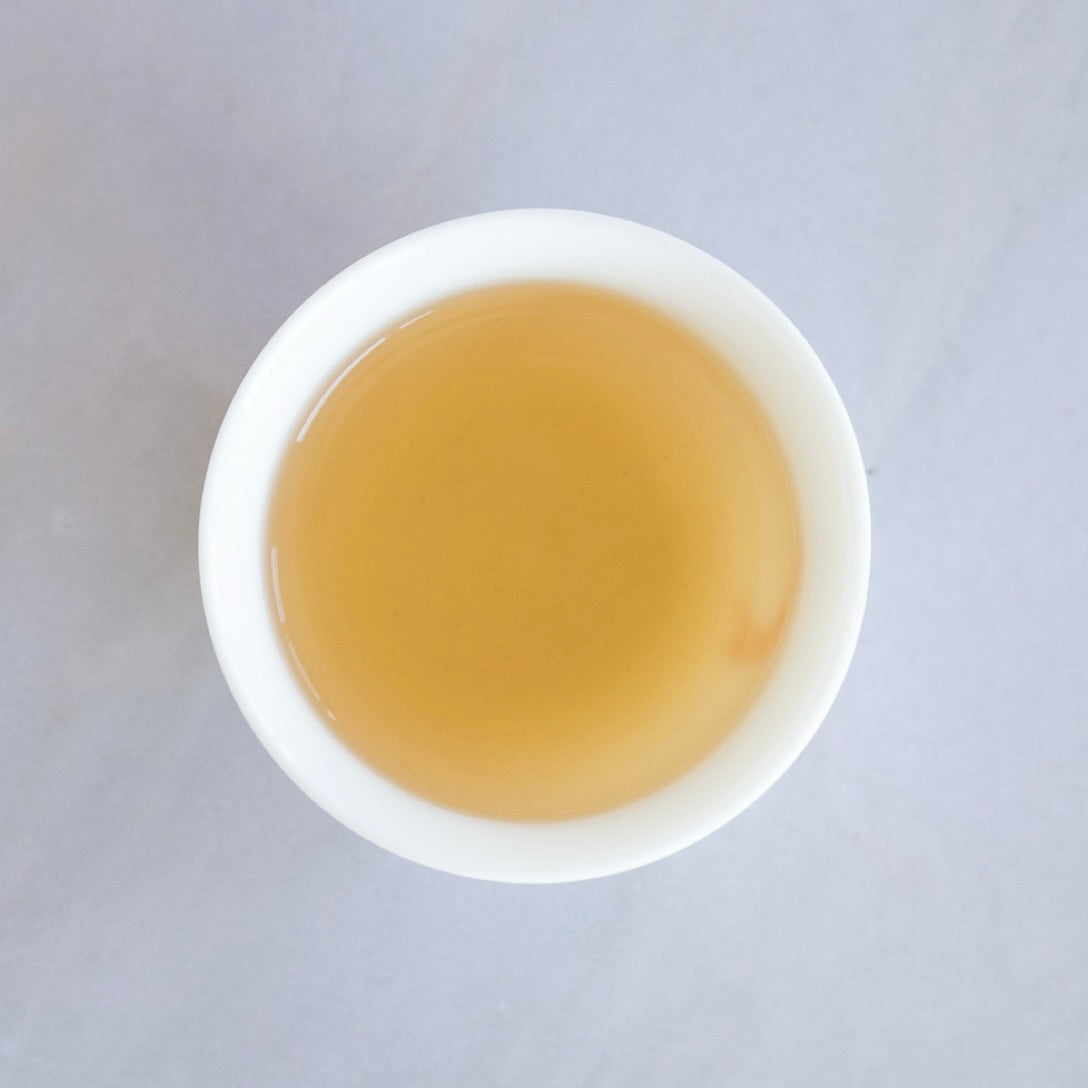 Light amber brewed Dong Ding oolong tea liquor in a tasting cup by Tea Studio Lu in Switzerland