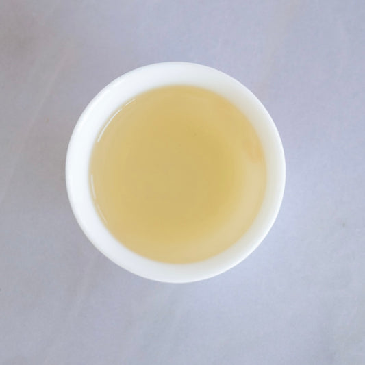 Freshly brewed golden Jin Xuan oolong tea served in a white porcelain cup from Tea Studio Lu Switzerland