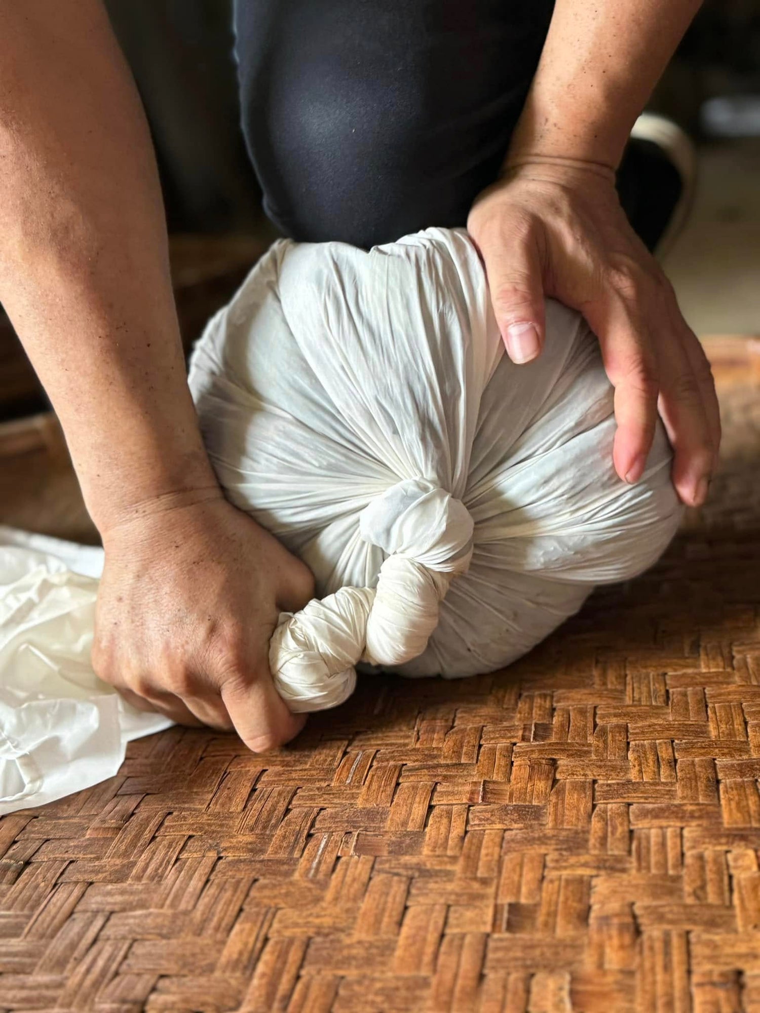 Artisan hands traditional cloth-rolling oolong tea leaves on a bamboo tray by Tea Studio Lu in Geneva, Switzerland