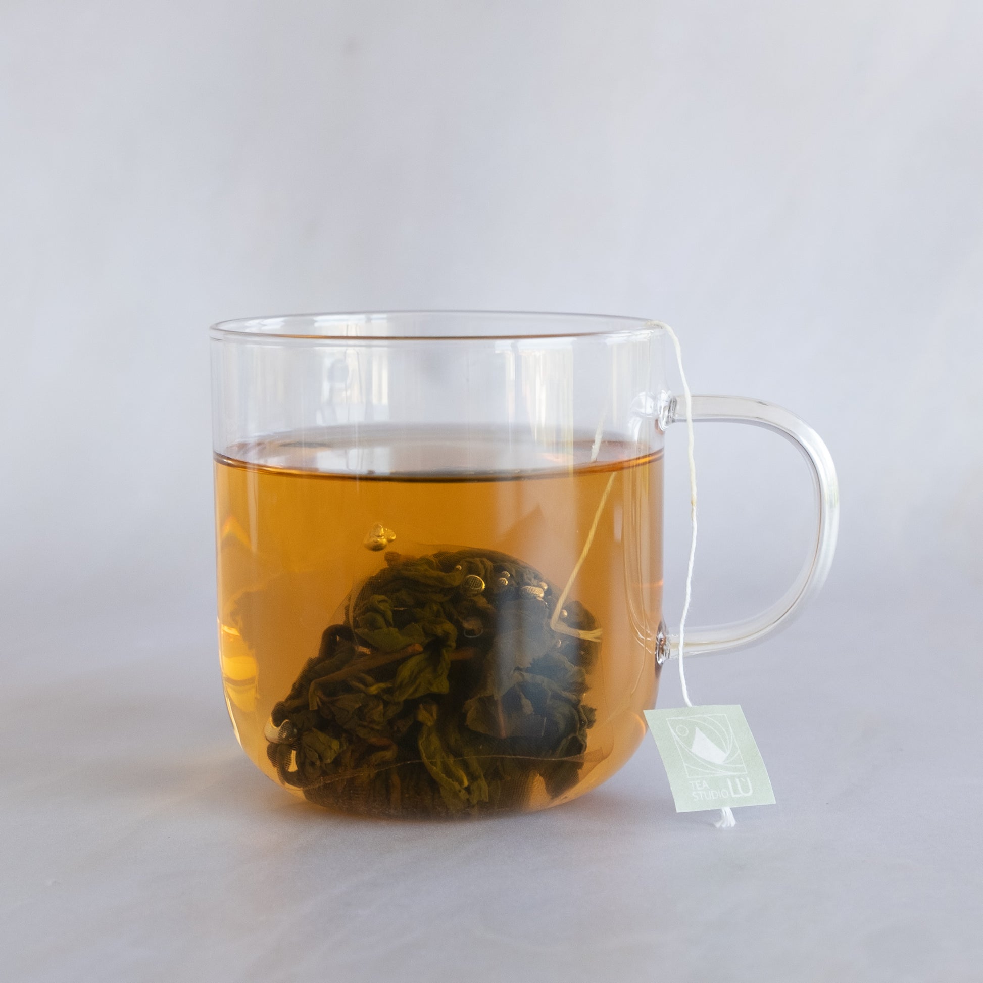 Steeped loose-leaf oolong tea expanding inside a biodegradable pyramid sachet in Geneva, Switzerland 