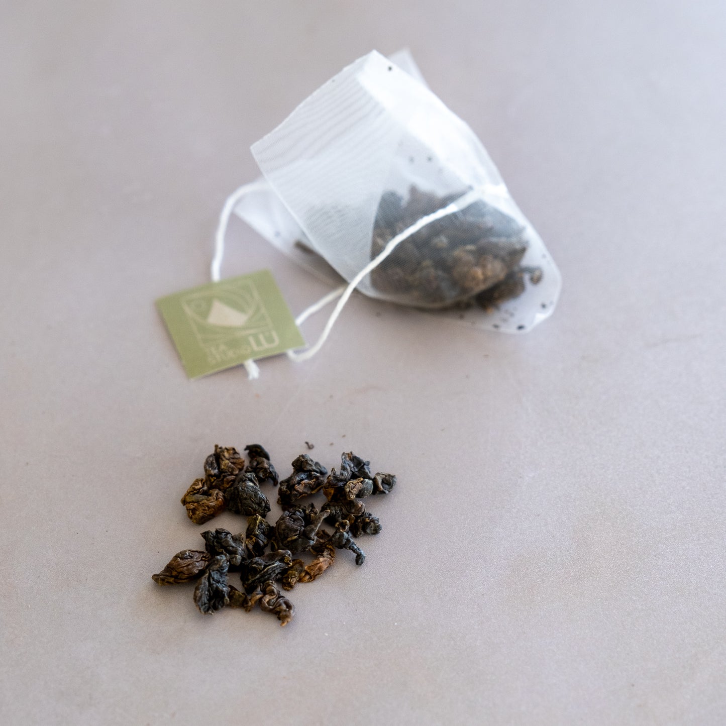 Tea Studio Lu eco-friendly pyramid tea bag with green brand tag placed on surface in Geneva