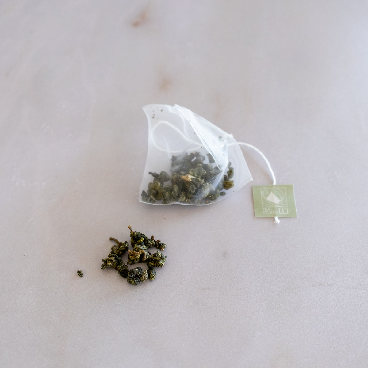 Whole-leaf oolong tea inside a mesh pyramid filter sachet from local tea shop Tea Studio Lu in Switzerland